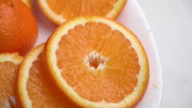 Portakal dilimi yavaş çekimde beyaz bir tabağa düşüyor. Olgun organik narenciye meyveleri. Sağlıklı yeme kavramı