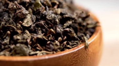 Tahta bir kasede kurumuş yeşil çay yaprakları. Organik içecekler. Bitkisel içecek konsepti. Makro. Döndürme