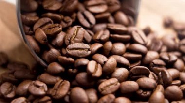 Fırınlanmış Arabika kahve çekirdekleri metal bir fincandan. Makro atış. Döndürme