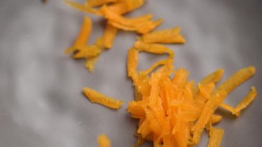 Ağır çekimde rendelenmiş organik balkabağı parçalarını boş bir mutfak kâsesine düşürmek. Sağlıklı sebze lifleri