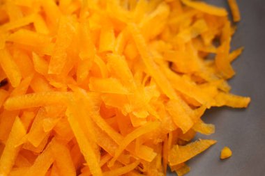 İnce portakal şeritli rendelenmiş tereyağlı kabak. Parçalanmış organik sebze. Mutfak kasesinde çiğ balkabağı parçaları. Makro