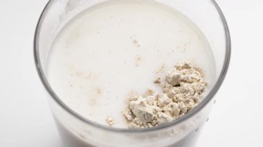 Smoothie 'de bitki bazlı protein tozu karıştırma kaşığı. Bardakla besin sıvısını karıştırıyorum. Sağlıklı beslenme içeceği. Yakın plan.