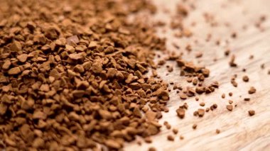 Tahta bir yüzeye saçılmış saf hazır biyo kahve taneleri. Çiğ, çözünebilir organik içecek. Makro atış. Döndürme