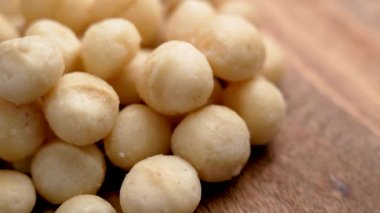 Ahşap yüzeyde kavrulmuş macadamia fındıkları. En iyi gurme malzemesi. Makro. Döndürme