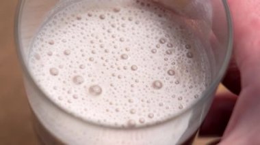 Köpüklü böğürtlen proteinli milkshake bardağı yakın plan.