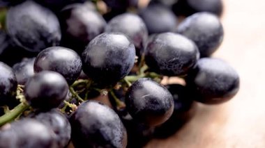 Kırsal ahşap bir yüzeyde çekirdeksiz siyah üzüm. Doğal antioksidan ve besinlerle organik dut topladım. Makro. Döndürme