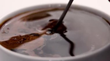 Metal kaşıkla beyaz fincanda eritilmiş hazır granüle kahve karıştırmak. Sıcak su yüzeyinde karanlık girdaplar. Çabucak canlandırıcı bir sabah içkisi hazırlıyorum. Zengin aroma ve koyu renk.