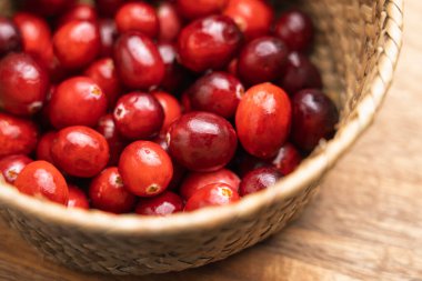 Kırsal dokuma sepetinde taze toplanmış kızılcıklar (aşı makrokarponu). Organik kırmızı meyveler. Doğal çiftlikten sofraya üretim konsepti. Üst görünüm