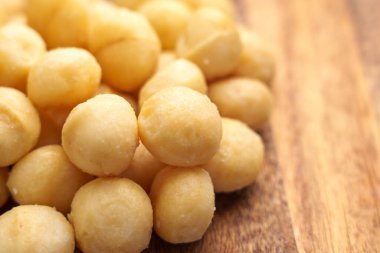 Ahşap yüzeyde Macadamia fındıkları. Sağlıklı yağ ve besinlerle birlikte doğal besleyici atıştırmalıklar. Yakın plan.