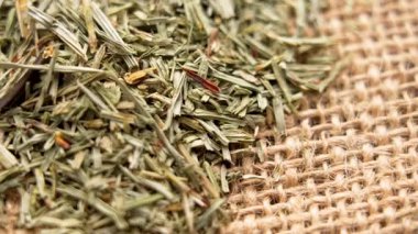 Kırsal çuval bezi yüzeyine saçılmış kurumuş at kuyruklu otlar. Geleneksel tıbbi ezilmiş bitki. Bitkisel çay malzemesi. Makro atış. Üst Manzara. Döndürme