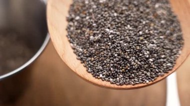Masadaki metal mutfak malzemelerinin üzerinde tahta kaşıkta Chia tohumları var. Sağlıklı beslenme için besin değeri yüksek süper yiyecekler. Organik bitki bazlı malzeme. Makro