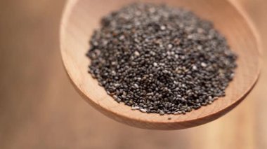 Kahverengi arka planda tahta kaşıkta Chia.