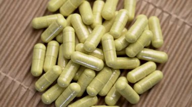 Kağıt arkaplanda yeşil quercetin kapsülleri. Bağışıklık desteği için bromelain özü içeren diyet takviyeleri. Üst Manzara. Döndürme