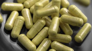 Siyah cam tabağa dökülen bromelin özlü yeşil quercetin kapsülleri. Bağışıklık desteği için beslenme takviyesi. Yavaş çekim