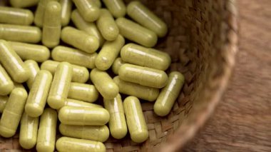 Bromelain ve quercetin kapsülleri ahşap arka planda çevre dostu hasır kasede. Bağışıklık sistemi için bitkisel özlerle dolu takviyeler. Döndürme. Üst görünüm