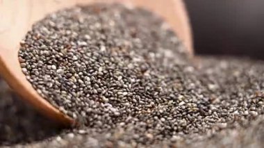 Tahta kaşıktan organik chia tohumları dökülüyor. Makro çekim