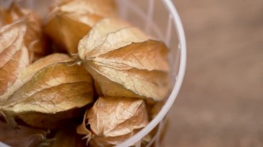 Burun Bektaşi (Physalis), ahşap bir masada plastik bir alışveriş sepetinde. Makro atış. Döndürme