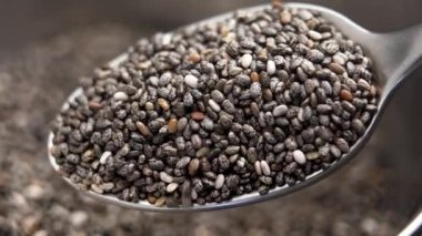 Metal kaşıkta makro boy besleyici chia tohumu. Süper yemek malzemesi. Yavaş çekim