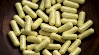 Tahta bir kasede yeşil ağrı kesici kapsülleri. Üst Manzara. Döndürme