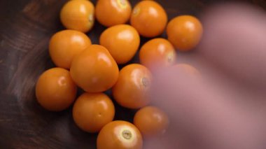 Bir gurme soyulmaya hazır Physalis Peruviana meyvelerini ahşap kaseden toplar. Böğürtlen Burnu