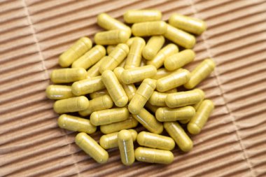 Kağıt arkaplanda yeşil quercetin kapsülleri. Bağışıklık desteği için bromelain özü içeren diyet takviyeleri. Üst görünüm. 