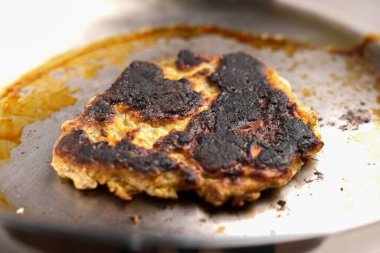 Çelik tavada kavrulmuş siyah kabuklu yanık krep. Ön görünüm