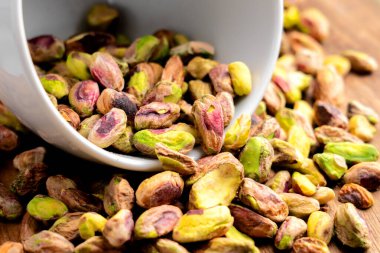 Beyaz bardaktaki soyulmuş şam fıstığı çekirdekleri doğal besleyici fındık yığınının içine konur. Makro çekim