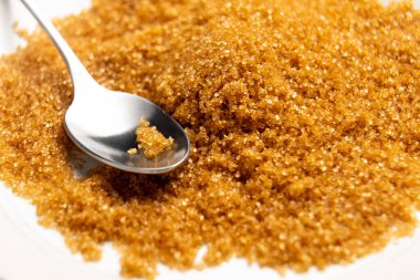 Tabakta çay kaşığı ile kristal kahverengi kamış şekeri. Makro çekim