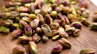 Soyulmuş şam fıstığı çekirdekleri yavaş çekimde ahşap masaya düşüyor. Kurutulmuş doğal fındık.