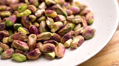 Ahşap masadaki mutfak kasesinde soyulmuş fıstık yığını. Döndürme