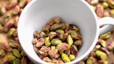 Kavrulmuş şam fıstığı çekirdekleri yavaş çekimde beyaz bardağa düşüyor. Doğal malzeme pişiriyorum.