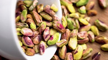 Ahşap masadaki beyaz bardaktan soyulan şam fıstığı taneleri. Organik besleyici fındık. Üst Manzara. Döndürme