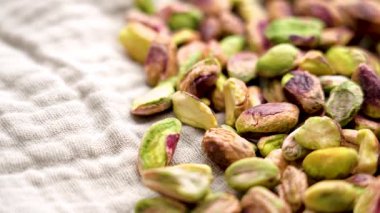 Fırınlanmış kabuklu fıstık, kumaş peçeteye serpiştirilmiş. Makro atış. Döndürme