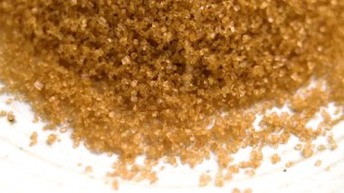 Organik kamış şeker kristalleri ağır çekimde dönen bir tabağa düşüyor.