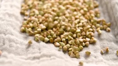 Çiğ karabuğday taneleri yavaş çekimde yumuşak bir peçeteye düşüyor. Pişmemiş organik malzeme.