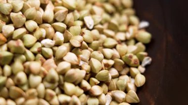 Kahverengi tahta kasede çiğ karabuğday taneleri. Pişmemiş organik kurutulmuş malzeme. Makro atış. Üst Manzara. Döndürme