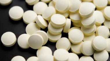 Siyah seramik yüzeye sarı ağrı kesici yığını. Makro atış. Döndürme