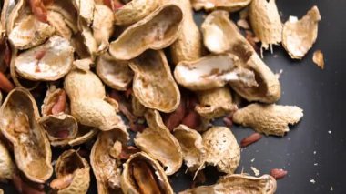 Boş fıstık kabukları, kabuğu soyulmuş fındıklar siyah mutfak tabağına düşüyor. Organik atık gübre bileşeni. Makro. Yavaş çekim