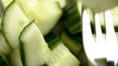 Çelik çatal ve taze organik salatalık hareketi. Sebze salatası malzemesi.