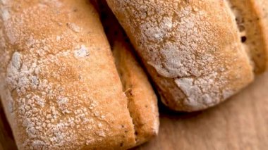 Siyah seramik tabakta altın çatlamış kabuklu taze buğday ekmeği. Makro atış. Döndürme