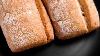 Siyah seramik mutfak tabağında çıtır çıtır çıtır iki çörek. Taze ekmek ruloları. Üst Manzara. Döndürme