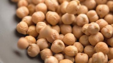 Pişmemiş nohutlar yavaş çekimde mutfak gri tabağına düşüyor. Çiğ protein yiyeceği. Makro atış. Legume ailesi
