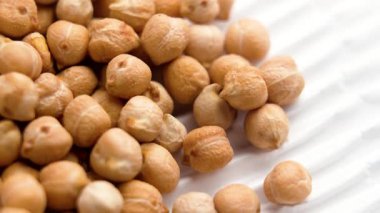 Beyaz kurdeleli kağıtta çiğ nohut. Pişmemiş bakkal malzemesi. Makro atış. Döndürme