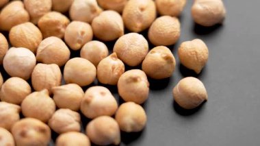 Siyah seramik tabakta kuru nohut fasulyesi. Makro. Pişmemiş protein lifleri diyet malzemesi. Döndürme