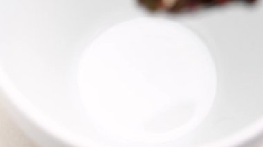 Bitkisel yeşil çay. Karışık amber çiçekleri ve papatya çiçekleri beyaz bardakta metal kaşıkla karıştırılmış. Makro