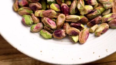 Ahşap sehpanın üzerinde seramik mutfak kasesinde soyulmuş şam fıstığı çekirdeği. Üst Manzara. Döndürme