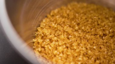 Kahverengi şeker kristalleri metal kabın içinde. Organik tatlı malzeme. Makro atış. Döndürme