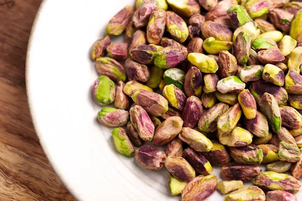 Ahşap sehpanın üzerinde seramik mutfak kasesinde soyulmuş şam fıstığı çekirdeği. Üst görünüm