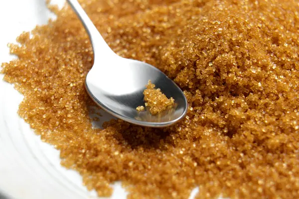 Metal kaşıkla bir kasede organik kahverengi kamış şekeri. Dağınık tatlı malzeme. Makro çekim. 