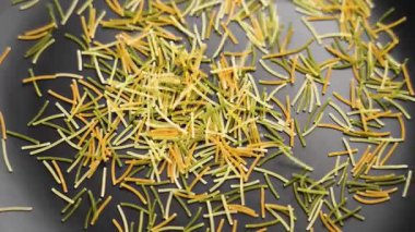 Siyah seramik tabağa dökülen siyah melek saçı. İtalyan pişmemiş makarna. Döndürme. Ağır çekim. Üst görünüm